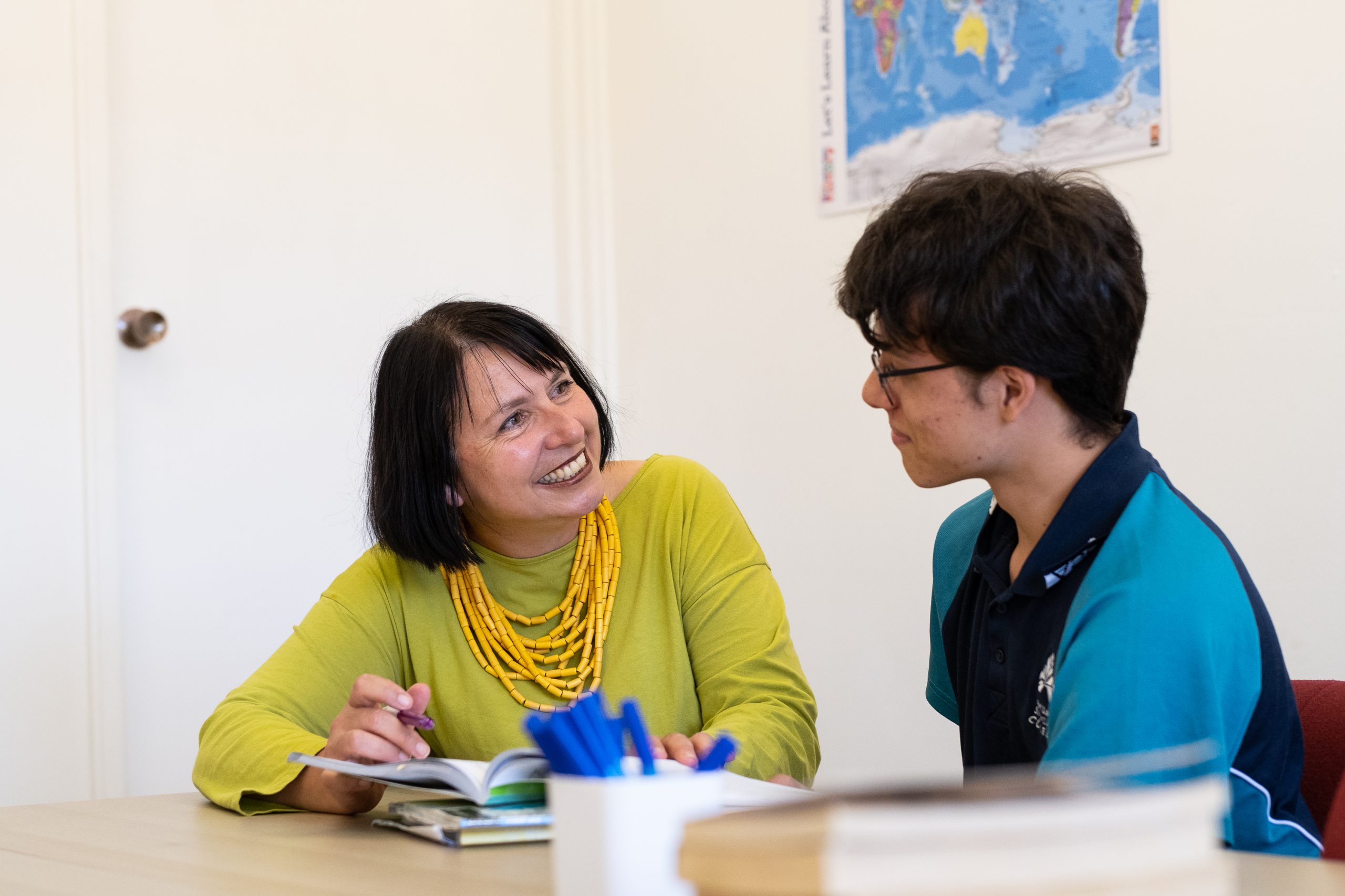 professional woman and teenage boy smiling at desk